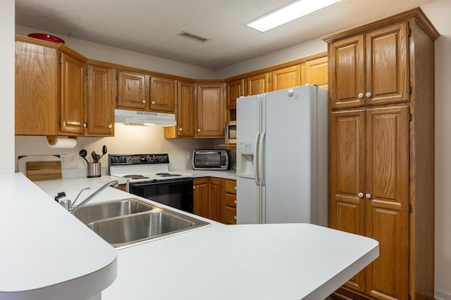 kitchen featuring a textured ceiling, white appliances, sink, and kitchen peninsula