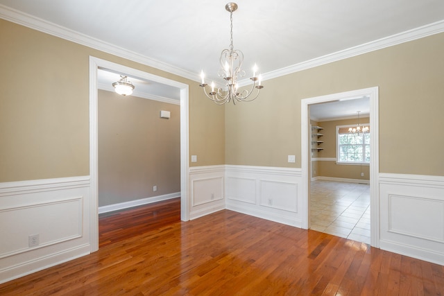 unfurnished room featuring crown molding, a chandelier, and hardwood / wood-style flooring