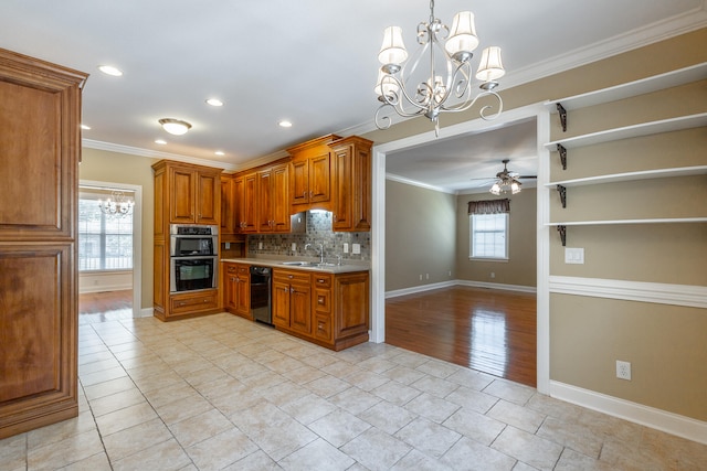 kitchen featuring ornamental molding, stainless steel double oven, ceiling fan with notable chandelier, and sink