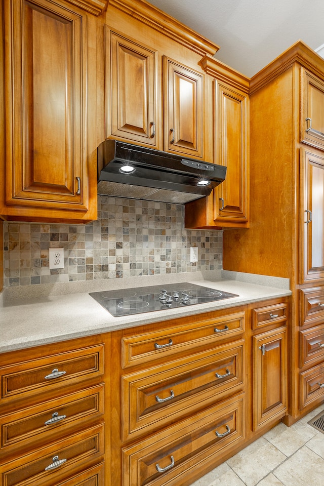 kitchen featuring backsplash, light tile patterned floors, and black electric stovetop