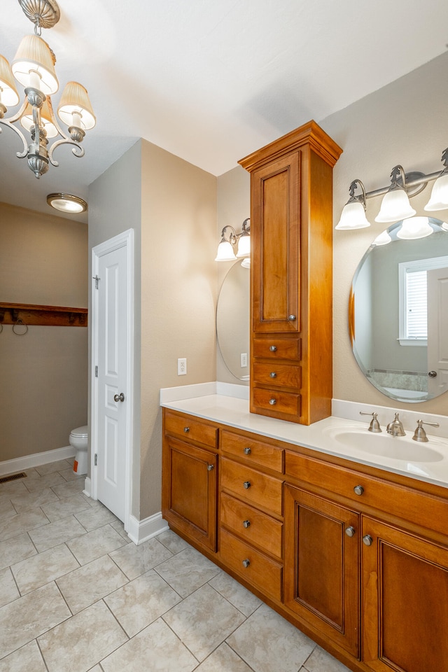 bathroom with an inviting chandelier, vanity, toilet, and tile patterned floors