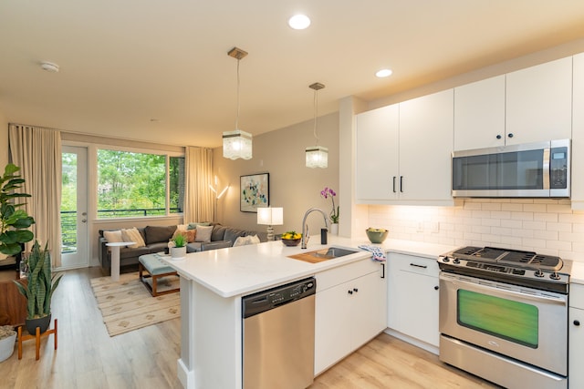 kitchen with light hardwood / wood-style floors, kitchen peninsula, appliances with stainless steel finishes, and sink