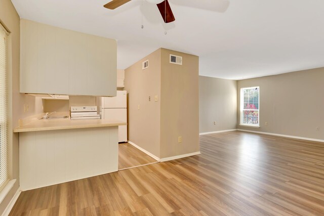 kitchen with light wood-type flooring, sink, kitchen peninsula, white appliances, and ceiling fan