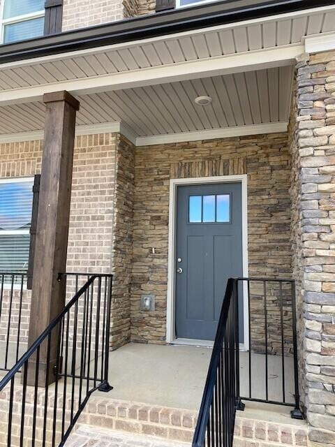 view of exterior entry with stone siding and brick siding