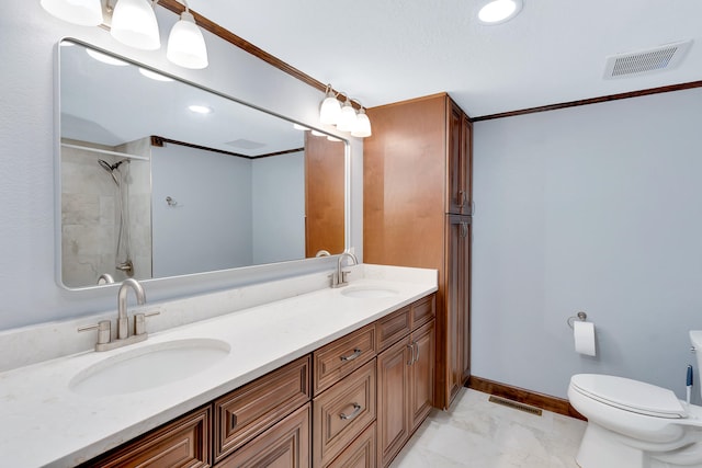 bathroom featuring ornamental molding, vanity, a tile shower, and toilet