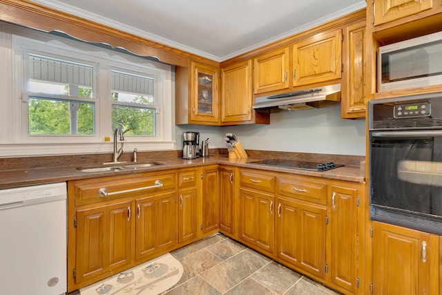 kitchen featuring dark stone counters, crown molding, sink, and black appliances