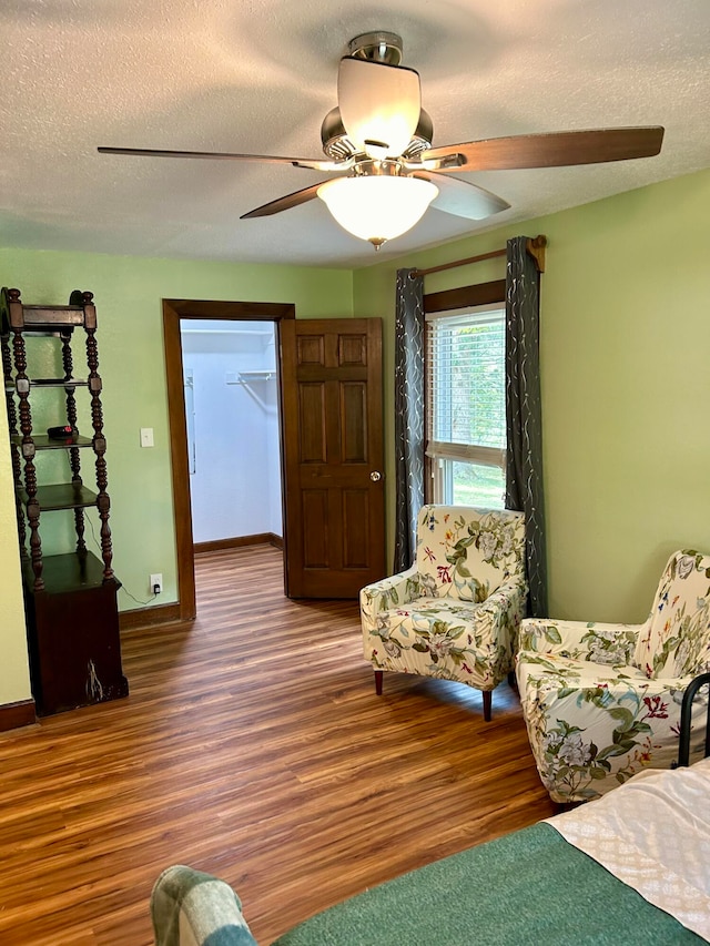 interior space featuring ceiling fan, a textured ceiling, wood-type flooring, and a spacious closet