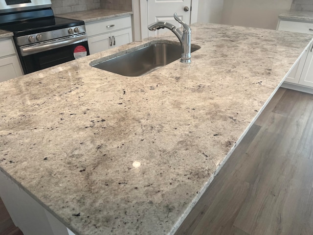 kitchen featuring electric stove, light stone countertops, and white cabinetry