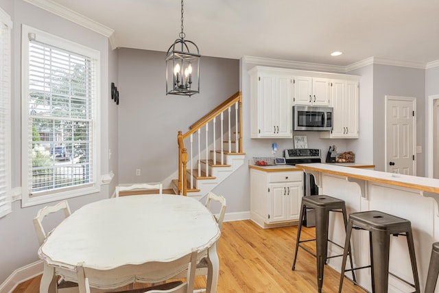 dining room featuring ornamental molding, a chandelier, and light hardwood / wood-style floors