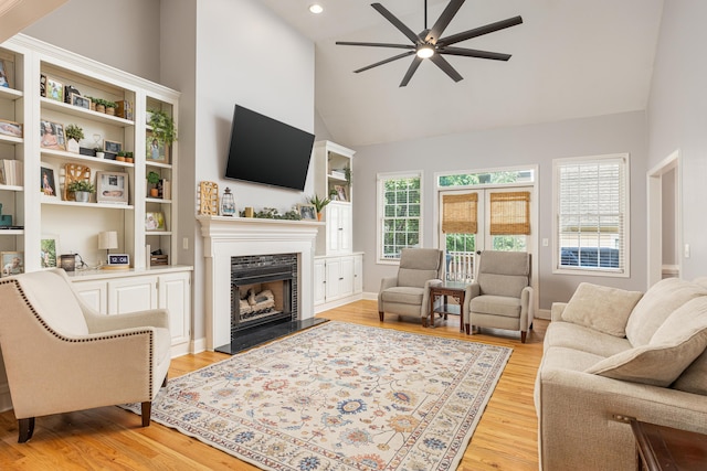 living room featuring light hardwood / wood-style flooring, ceiling fan, and high vaulted ceiling