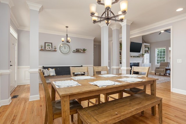 dining area featuring ceiling fan with notable chandelier, light hardwood / wood-style floors, ornamental molding, and ornate columns