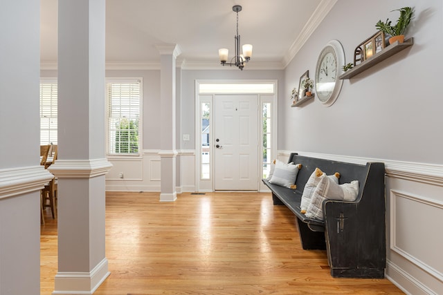 foyer with light hardwood / wood-style flooring, crown molding, decorative columns, and a chandelier