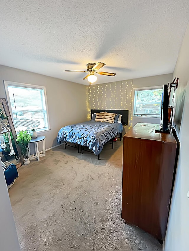 carpeted bedroom featuring a textured ceiling, multiple windows, a ceiling fan, and wallpapered walls