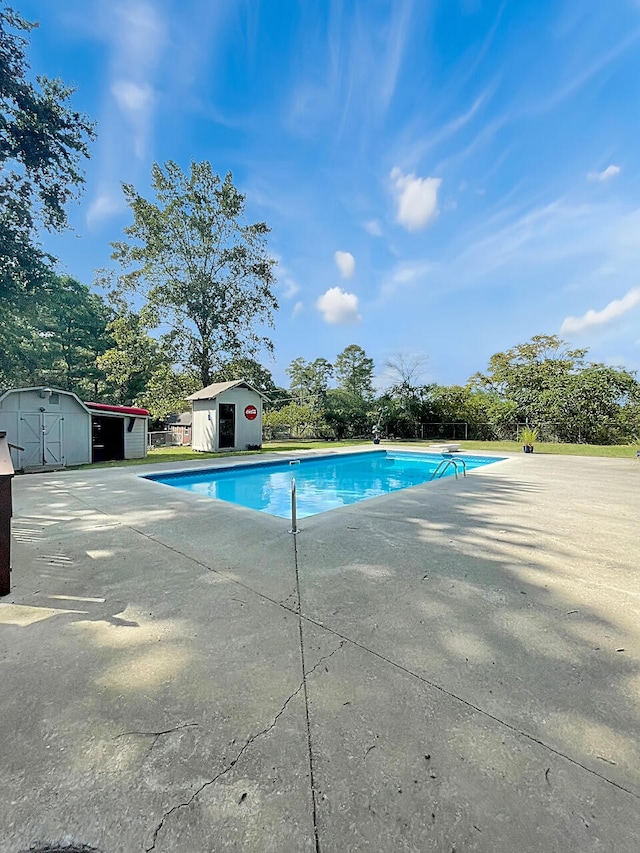 outdoor pool featuring an outbuilding, a patio, and a shed