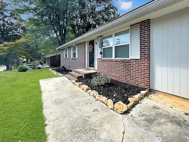 entrance to property with brick siding and a lawn