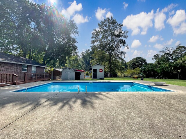 outdoor pool featuring a storage shed, a wooden deck, a diving board, and an outdoor structure