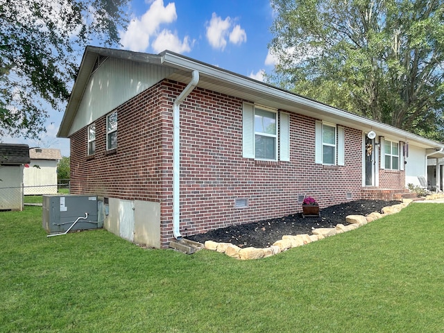 view of home's exterior featuring brick siding, a lawn, cooling unit, and fence