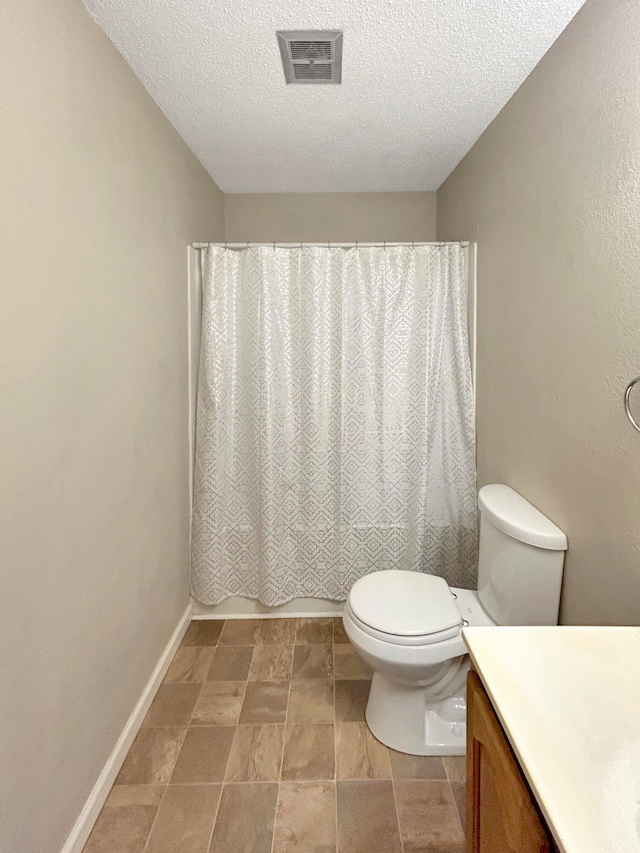 full bathroom featuring visible vents, toilet, vanity, a textured ceiling, and baseboards