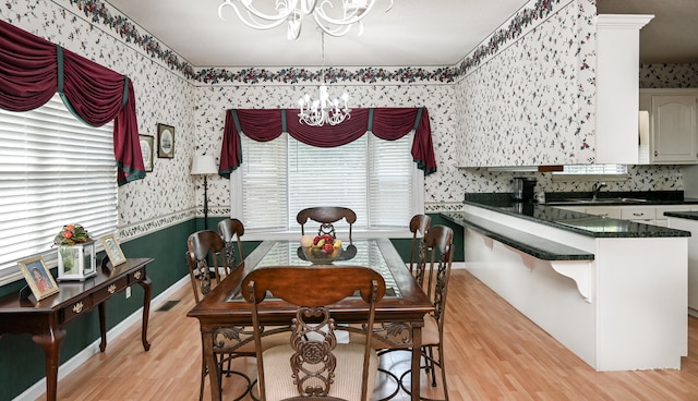 dining space featuring light hardwood / wood-style floors, a notable chandelier, and sink