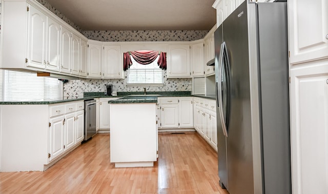 kitchen with white cabinets, stainless steel refrigerator with ice dispenser, a kitchen island, and light wood-type flooring