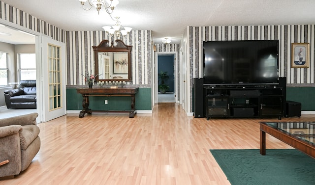 living room with an inviting chandelier, hardwood / wood-style flooring, and a textured ceiling