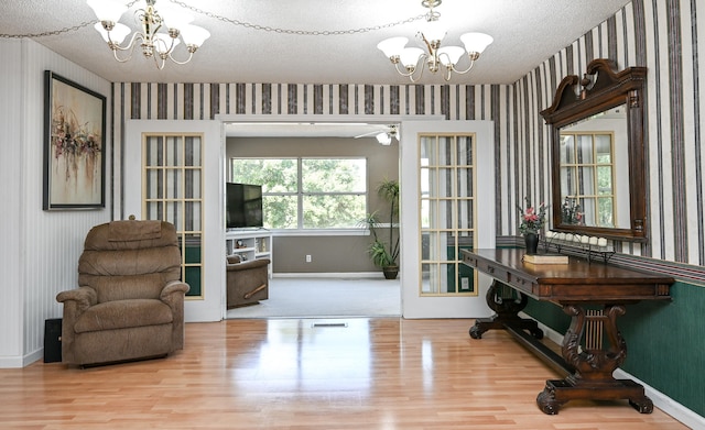 interior space with ceiling fan with notable chandelier, light hardwood / wood-style flooring, and a textured ceiling