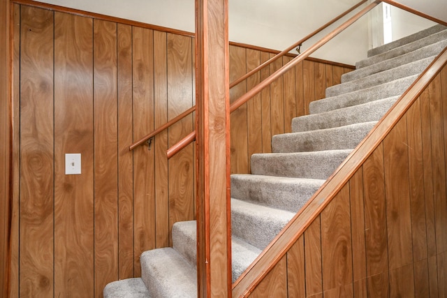 stairway featuring wood walls