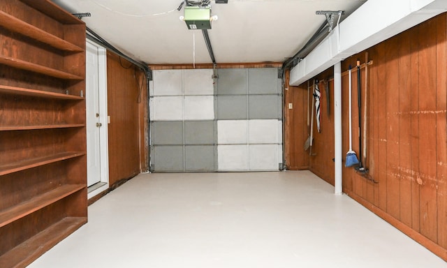 garage with a garage door opener and wood walls