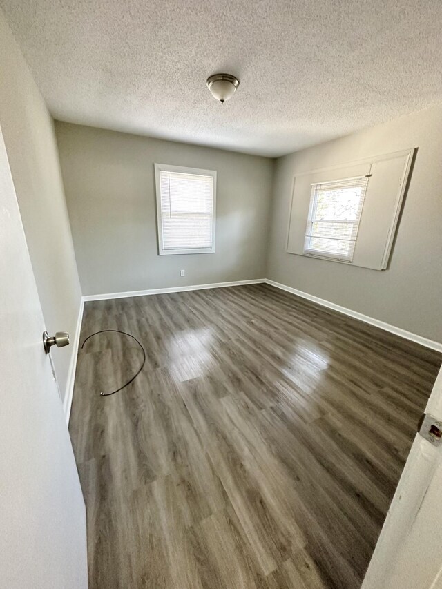 empty room with dark wood-type flooring and a textured ceiling