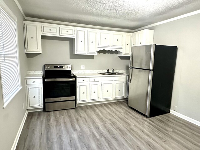 kitchen with sink, white cabinetry, a textured ceiling, light wood-type flooring, and appliances with stainless steel finishes