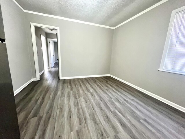 empty room featuring ornamental molding, a textured ceiling, and dark hardwood / wood-style flooring