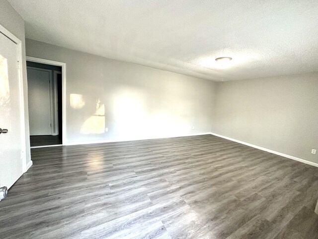 spare room featuring dark hardwood / wood-style flooring and a textured ceiling