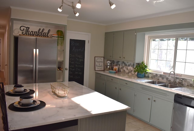 kitchen featuring decorative backsplash, light tile patterned flooring, stainless steel appliances, crown molding, and sink