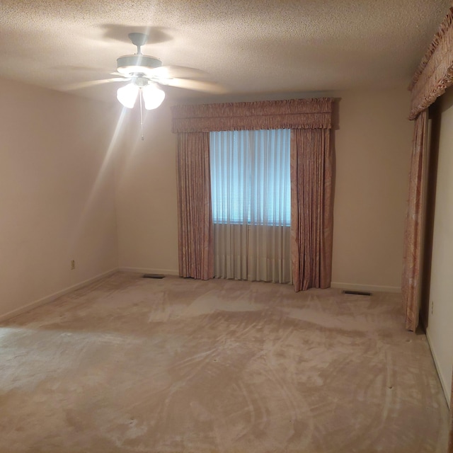 spare room featuring a textured ceiling, ceiling fan, and light colored carpet