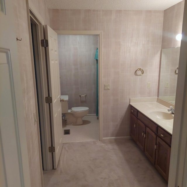 bathroom with a textured ceiling, vanity, and toilet