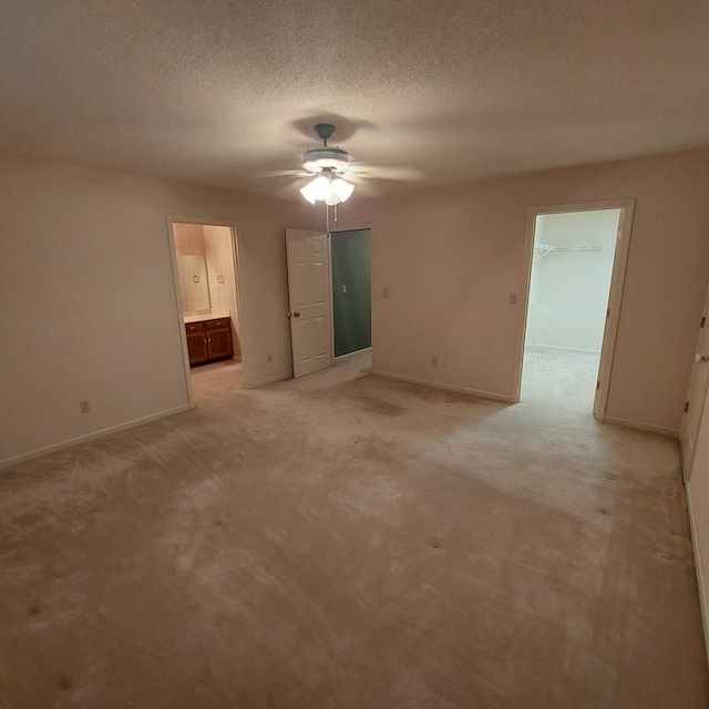 spare room featuring ceiling fan, light colored carpet, and a textured ceiling