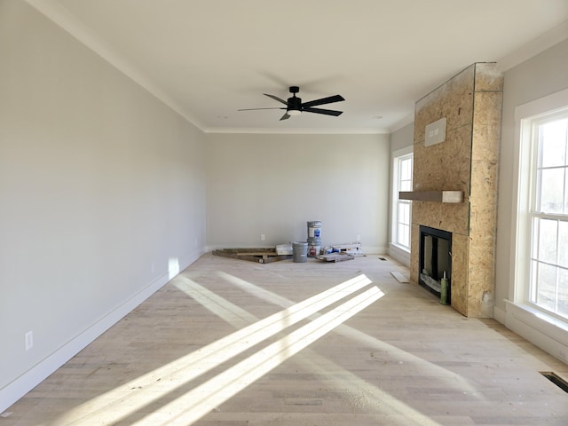 unfurnished living room featuring plenty of natural light, ornamental molding, and a fireplace