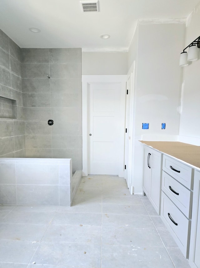 bathroom with a tile shower, vanity, and crown molding