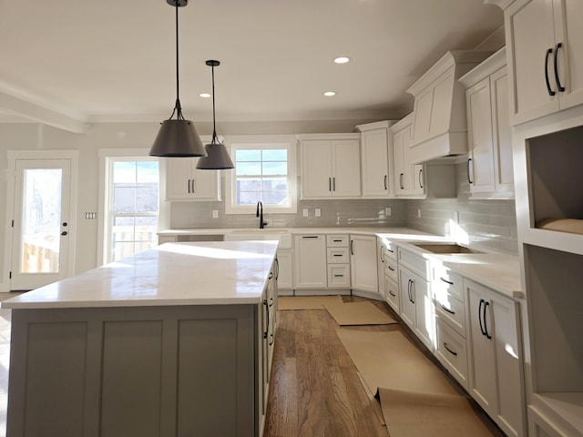 kitchen with pendant lighting, a center island, sink, and white cabinets