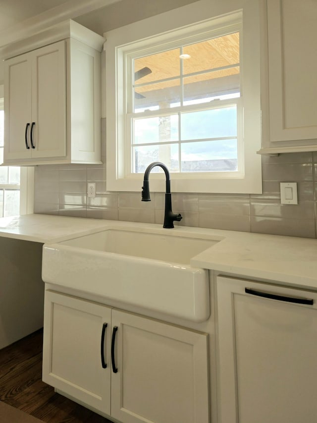 kitchen with white cabinetry, dishwasher, sink, decorative backsplash, and light stone counters