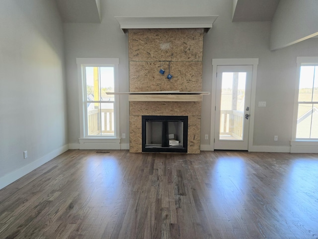 unfurnished living room featuring a wealth of natural light, a fireplace, and dark wood-type flooring