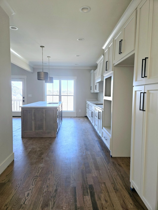 kitchen with hanging light fixtures, white cabinetry, a kitchen island, and plenty of natural light