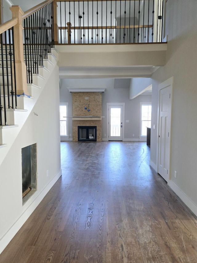 unfurnished living room with a towering ceiling, a fireplace, and dark hardwood / wood-style floors