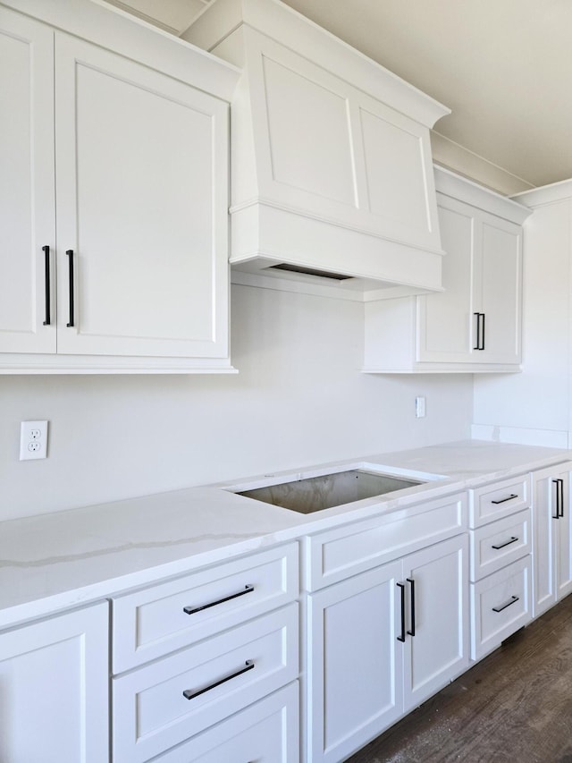 kitchen with stovetop, light stone countertops, dark wood-type flooring, and white cabinets