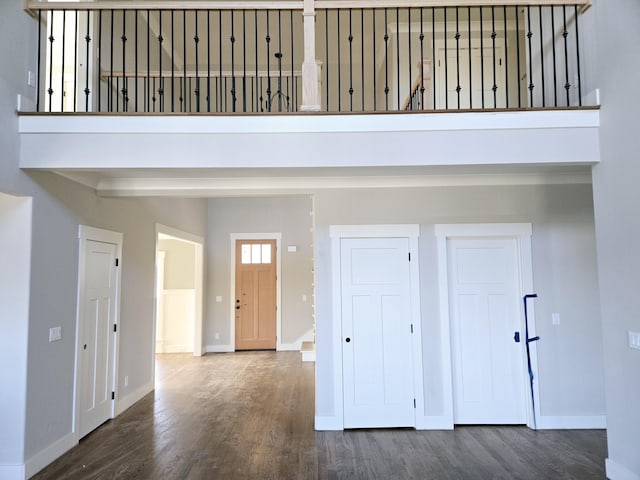 foyer entrance with beamed ceiling, dark hardwood / wood-style floors, and a towering ceiling