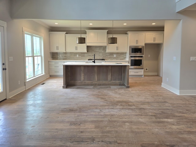 9877 Trestle Cir Unit 46, Ooltewah, TN 37363 - kitchen featuring white cabinetry, baseboards, light countertops, an island with sink, and light wood finished floors