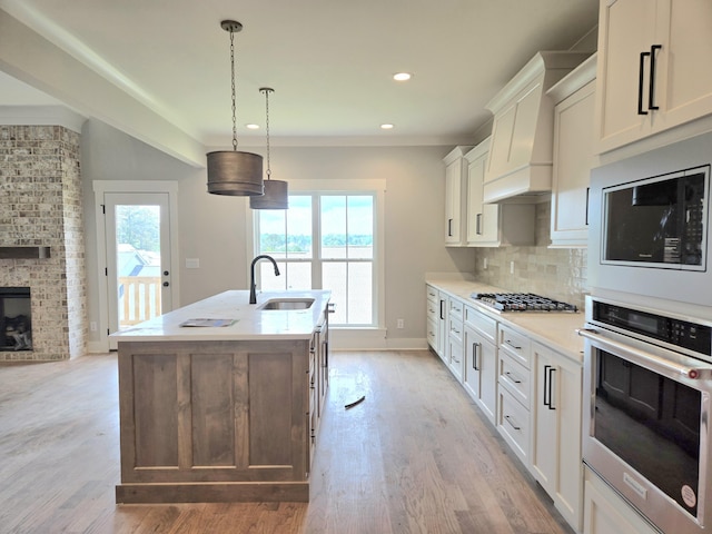 9877 Trestle Cir Unit 46, Ooltewah, TN 37363 - kitchen featuring appliances with stainless steel finishes, a sink, an island with sink, light countertops, and light wood-style floors
