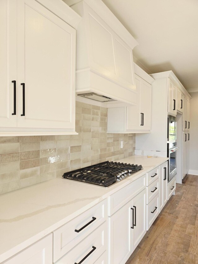 9877 Trestle Cir Unit 46, Ooltewah, TN 37363 - kitchen featuring appliances with stainless steel finishes, backsplash, white cabinetry, light stone countertops, and light wood-style flooring