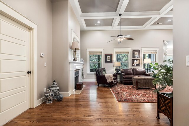 living room featuring beam ceiling, coffered ceiling, dark wood-type flooring, and ceiling fan