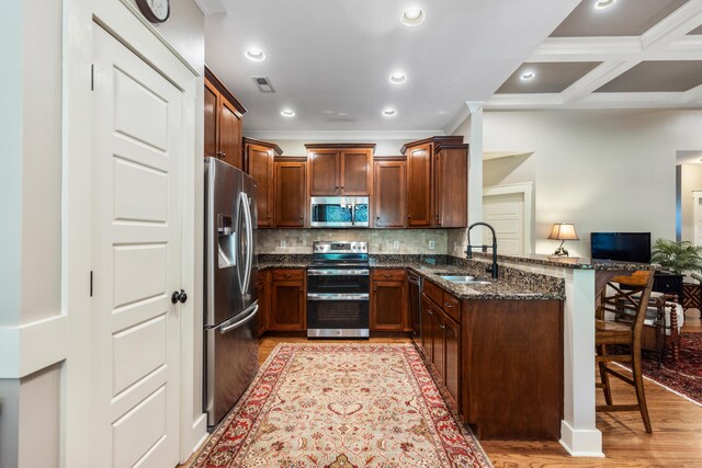 kitchen with kitchen peninsula, a breakfast bar, light hardwood / wood-style flooring, sink, and stainless steel appliances